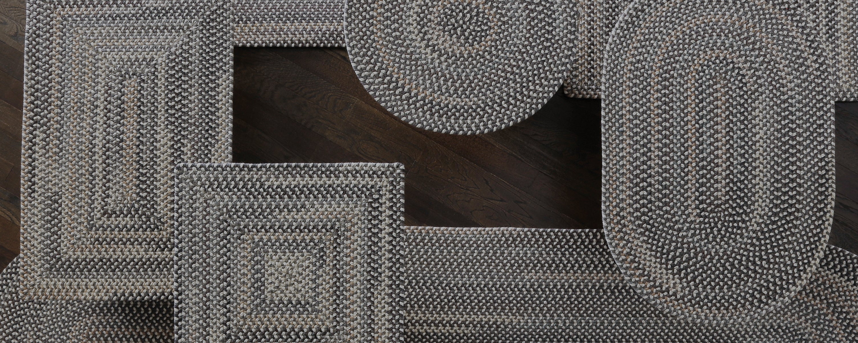 various shapes of gray braided rug collaged on dark wood floor